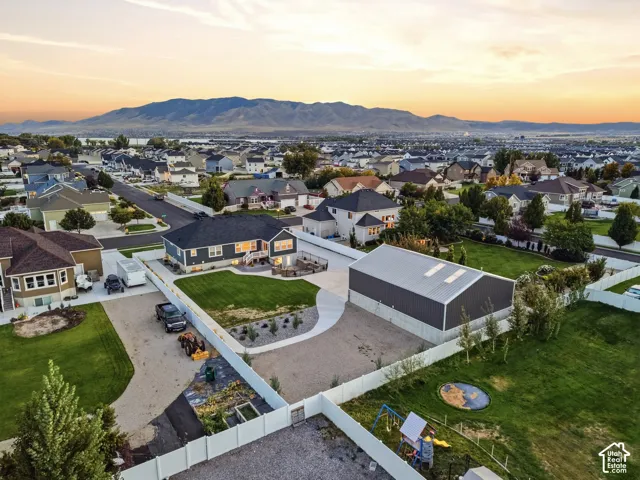 Two-story residence with a dark-tone exterior, concrete driveway, and an expansive detached auxiliary structure featuring a metal roof