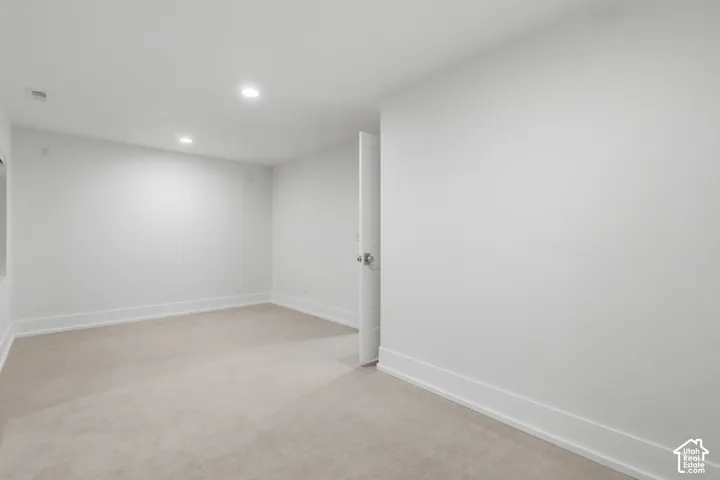 Neutral wall color, recessed lighting, and light-toned carpeting