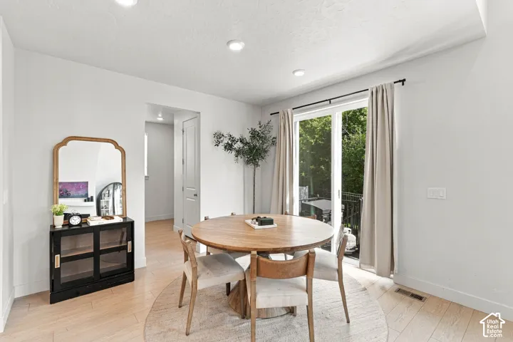 Light wood-finish flooring, recessed lighting, white walls, and sliding glass doors with direct outdoor access