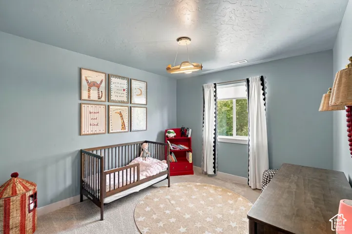 Carpeted flooring, single window with trim, light blue wall paint, textured ceiling, and recessed lighting
