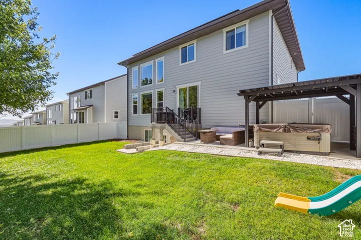 Expansive green lawn with a white privacy fence, multi-level patio, and a shaded pergola