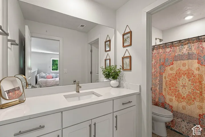 White vanity with brushed nickel hardware, integrated rectangular sink, large wall-mounted mirror, and recessed lighting