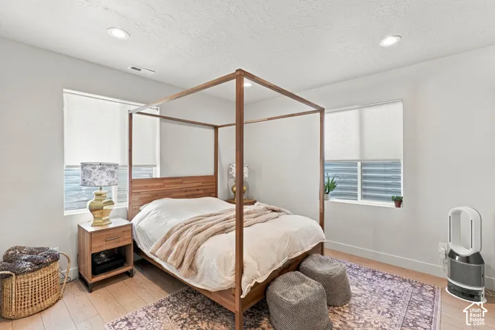 Recessed lighting, wood-finish flooring, two windows with roller shades, and light-toned wall finishes