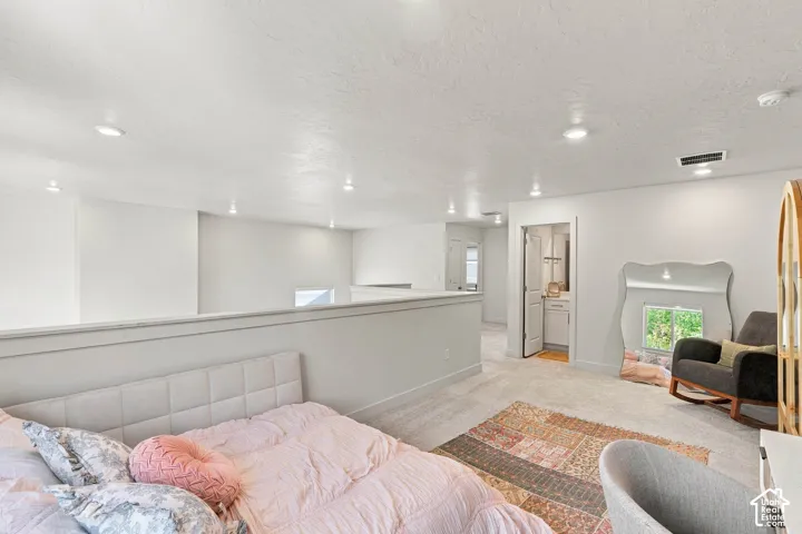 Open loft area with recessed lighting, light-toned carpeting, and a half-wall partition