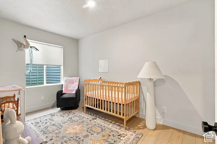 Hardwood-style flooring with light-toned walls and a window with roller shades