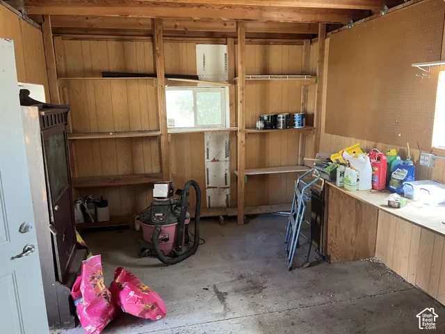 Built-in wood shelving, exposed wood beam ceiling, wood-finish wall paneling, and an integrated workbench with pegboard backing