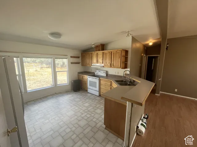Laminate countertops with a double basin sink, white range, and recessed lighting
