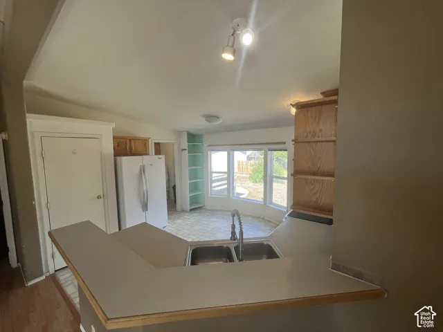 Kitchen featuring a double basin stainless steel sink with a pull-down faucet, a built-in breakfast bar, wood-finish cabinetry, and recessed lighting