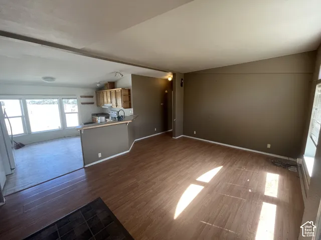 Open-concept living area with wood-finish flooring, a breakfast bar, and a kitchen featuring wood cabinetry