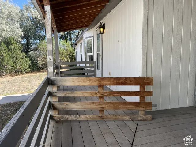 Covered wooden porch with exposed rafters and an exterior wall light fixture