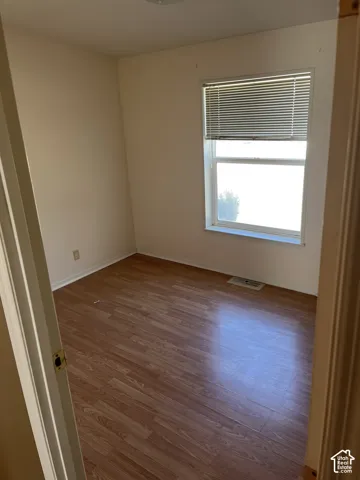 Room featuring wood-finish flooring, neutral wall paint, and a window with blinds