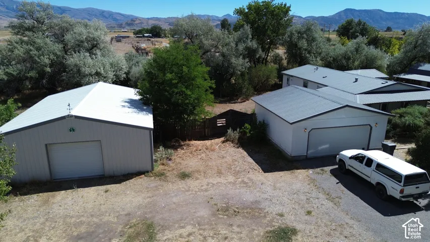 Metal-sided detached garage with a roll-up door, a separate attached garage with a roll-up door, and metal roofing on all structures