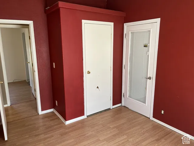 Wood-finish flooring, vibrant red walls, built-in closet, and a glass-paneled door