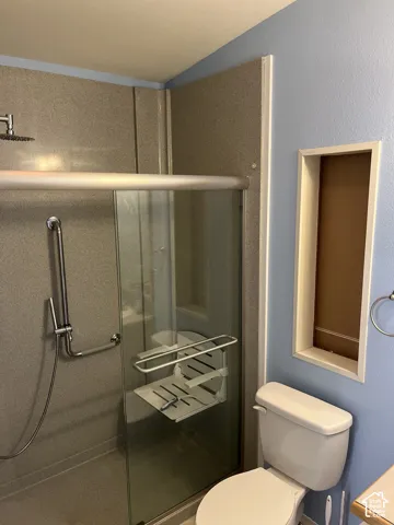 Walk-in shower with a rain shower head, hand-held shower, grab bars, and a built-in folding bench
