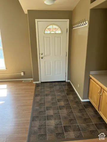 Entryway featuring a decorative transom window, white paneled door, and two-tone tile flooring