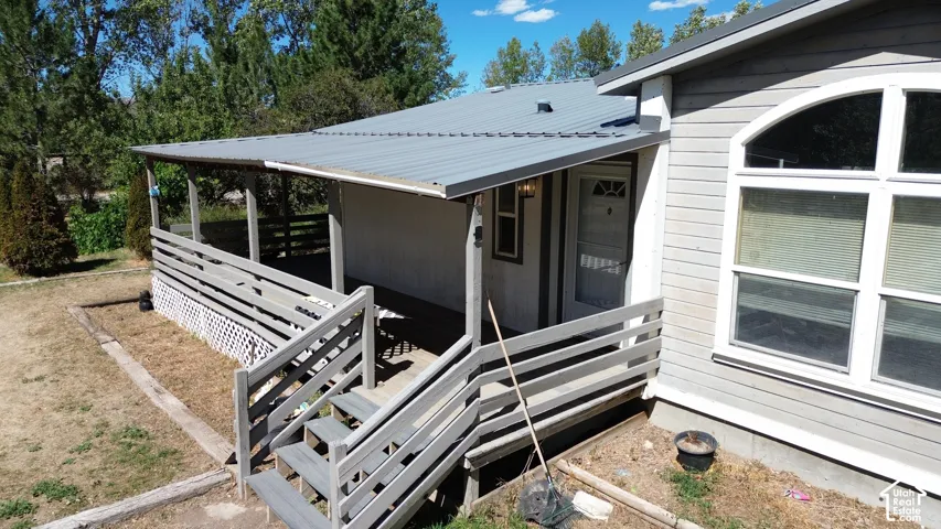 Covered front porch with wood railings, metal roof, and wood siding