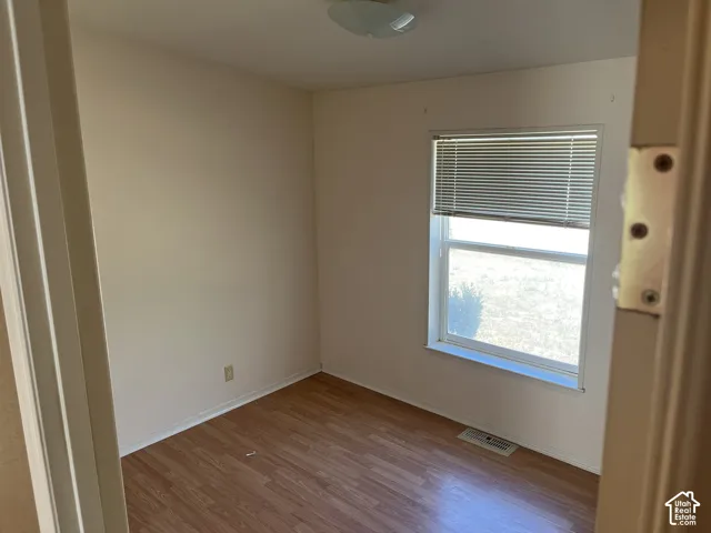 Wood-finish flooring with neutral wall tones and a window featuring blinds
