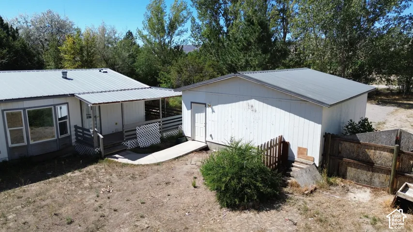 Property featuring a metal roof, covered porch with lattice accents, and an exterior storage building