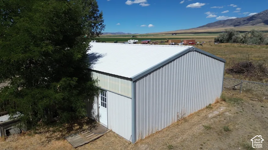 Metal-sided structure featuring a white metal roof and a white entry door with glass panes