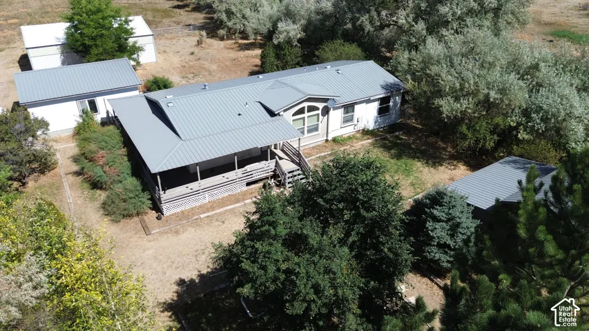 Metal roof main residence, covered front porch, arched window, and two detached outbuildings, surrounded by mature trees