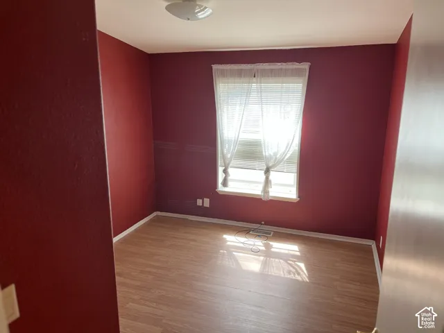 Wood-finish flooring with white trim and a single window