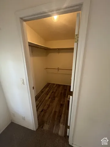 Walk-in closet featuring wood-finish flooring, built-in shelving, and a clothing rod