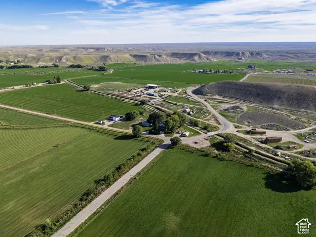Expansive green fields, paved roads, and distant bluffs frame this property