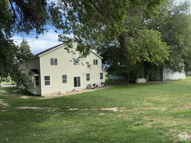 Rear exterior with light-colored siding, multiple windows, and a sliding glass door