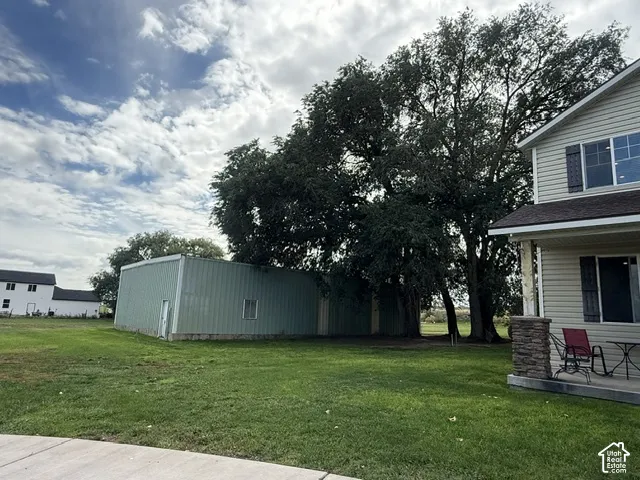 Two-story siding exterior with dark shutters, covered porch with stone column, and expansive grassy area