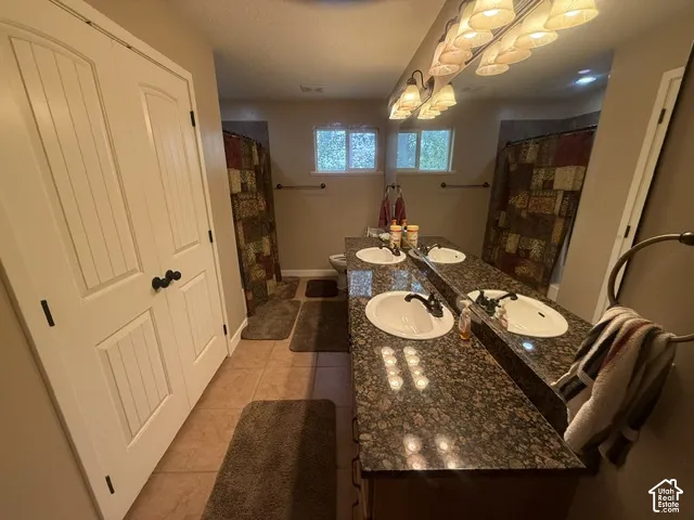 Double vanity with a dark granite countertop and undermount sinks, flanked by paneled doors and tile flooring