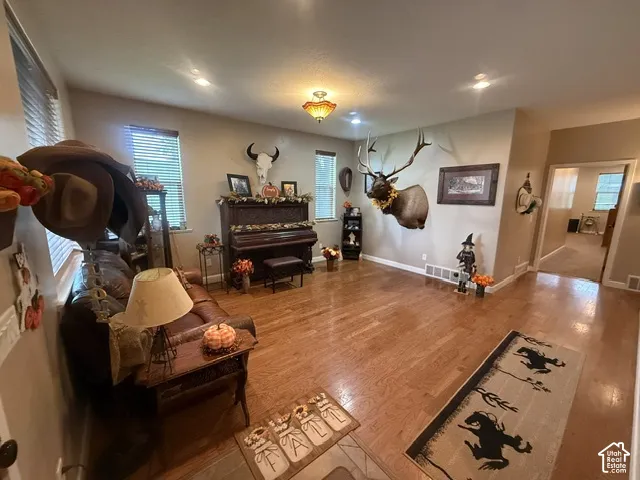 Hardwood flooring throughout, recessed lighting, and multiple windows with blinds