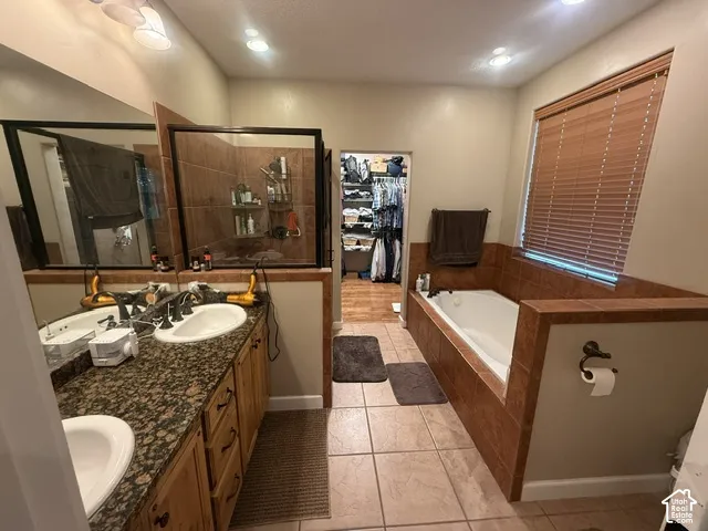 Dual vanity with stone-finish countertop, built-in soaking tub with tile surround, and enclosed shower with glass panels