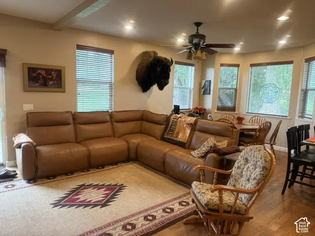 Recessed lighting, wood-finish flooring, ceiling fan, multiple windows with blinds, and exposed beam accent