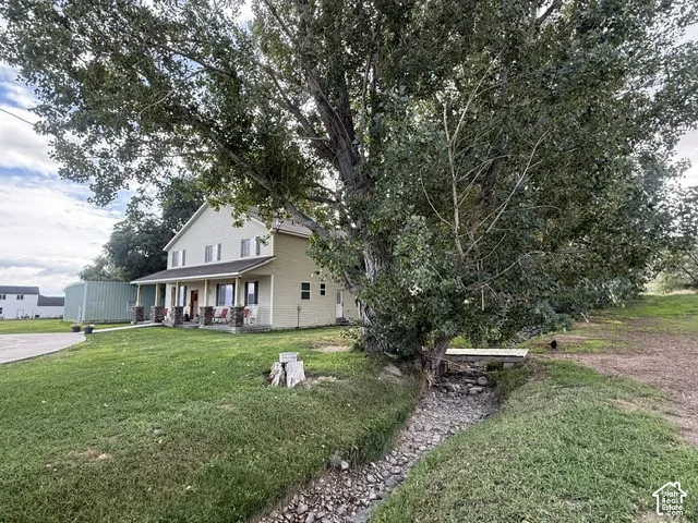 Expansive front lawn with mature trees and a covered porch