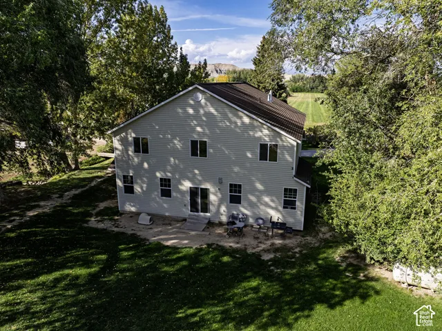 Two-story residence with light-colored siding, a dark metal roof, and multiple windows