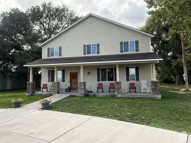 Two-story residence featuring light-colored siding and a covered front porch with stone-wrapped pillars
