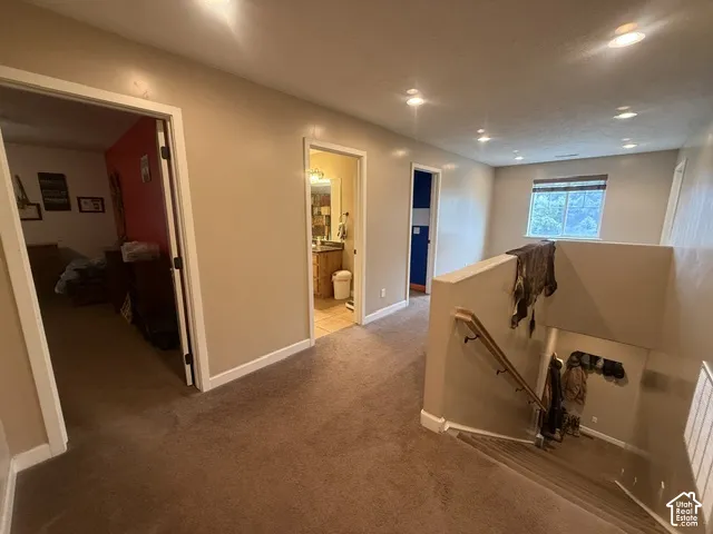 Carpeted hallway with recessed lighting, multiple doorways, and a window overlooking exterior greenery