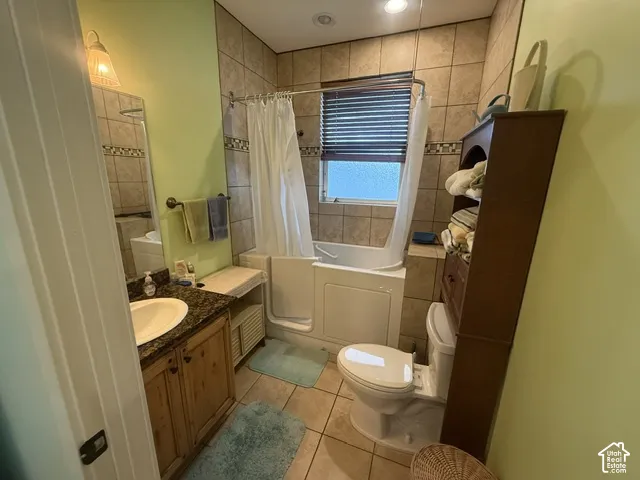 Bathroom featuring a tiled shower surround, built-in tub, vanity with a stone countertop, and tile flooring