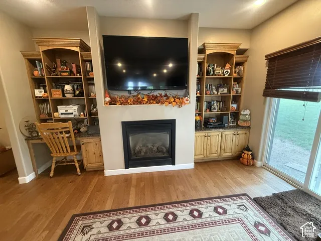 Hardwood flooring, built-in shelving, built-in cabinetry, built-in desk, and a built-in fireplace