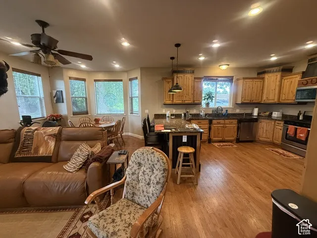 Open-concept living space with wood-finish flooring, recessed lighting, and a ceiling fan