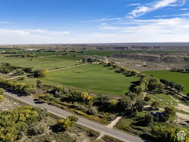 Expansive land featuring green fields, mature trees, and a distant road