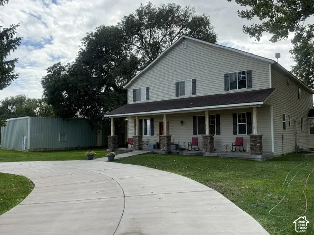 Two-story residence with light-colored siding and a covered front porch featuring stone-clad pillars