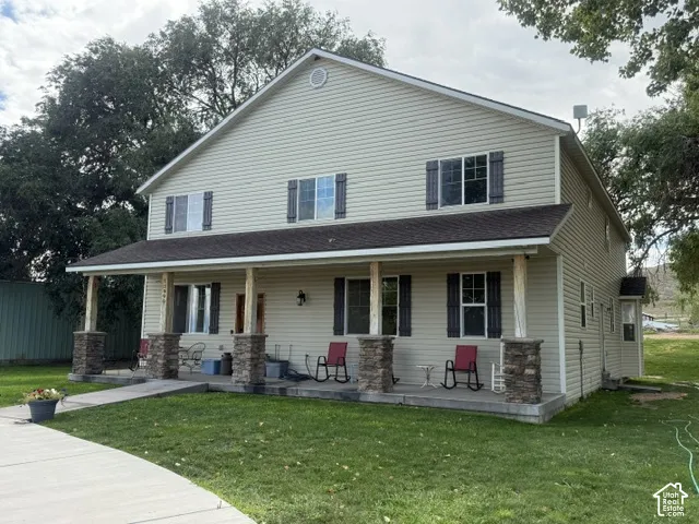 Two-story exterior with light-colored siding, contrasting dark shutters, and a covered porch