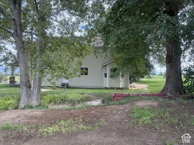 Siding exterior with multiple windows, covered porch with stone columns, and surrounding landscaping