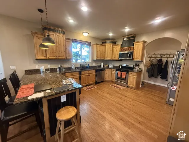 Kitchen featuring wood-finish flooring, granite-style countertops, wood cabinetry, stainless steel appliances, and recessed lighting