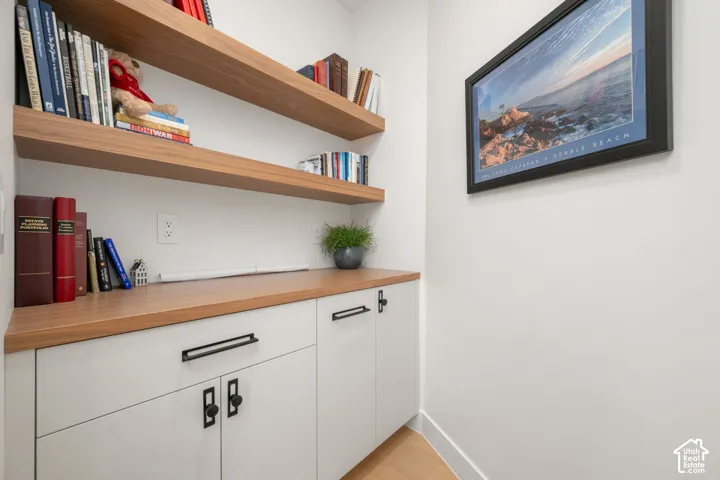 Built-in cabinetry with a wood-finish countertop, two floating wood-finish shelves, and black hardware