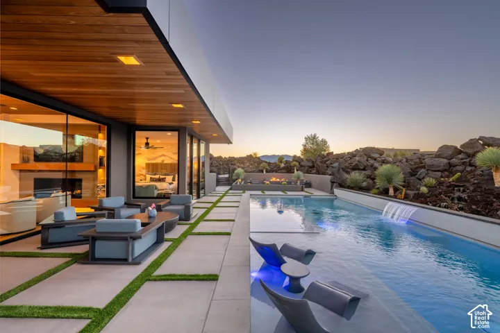 Expansive outdoor living area featuring a swimming pool with integrated waterfall and fire pit