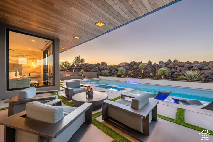 Expansive outdoor living area featuring a swimming pool, integrated spa, and a built-in fire pit