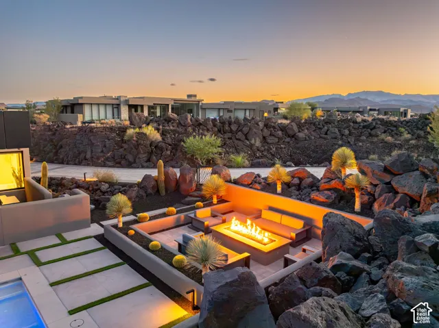 Outdoor living area featuring a sunken fire pit, built-in seating, concrete paver patio, and integrated landscape lighting