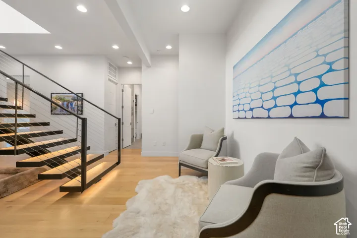 Hardwood flooring, recessed lighting, modern open-riser staircase with cable railing, skylight, and white walls